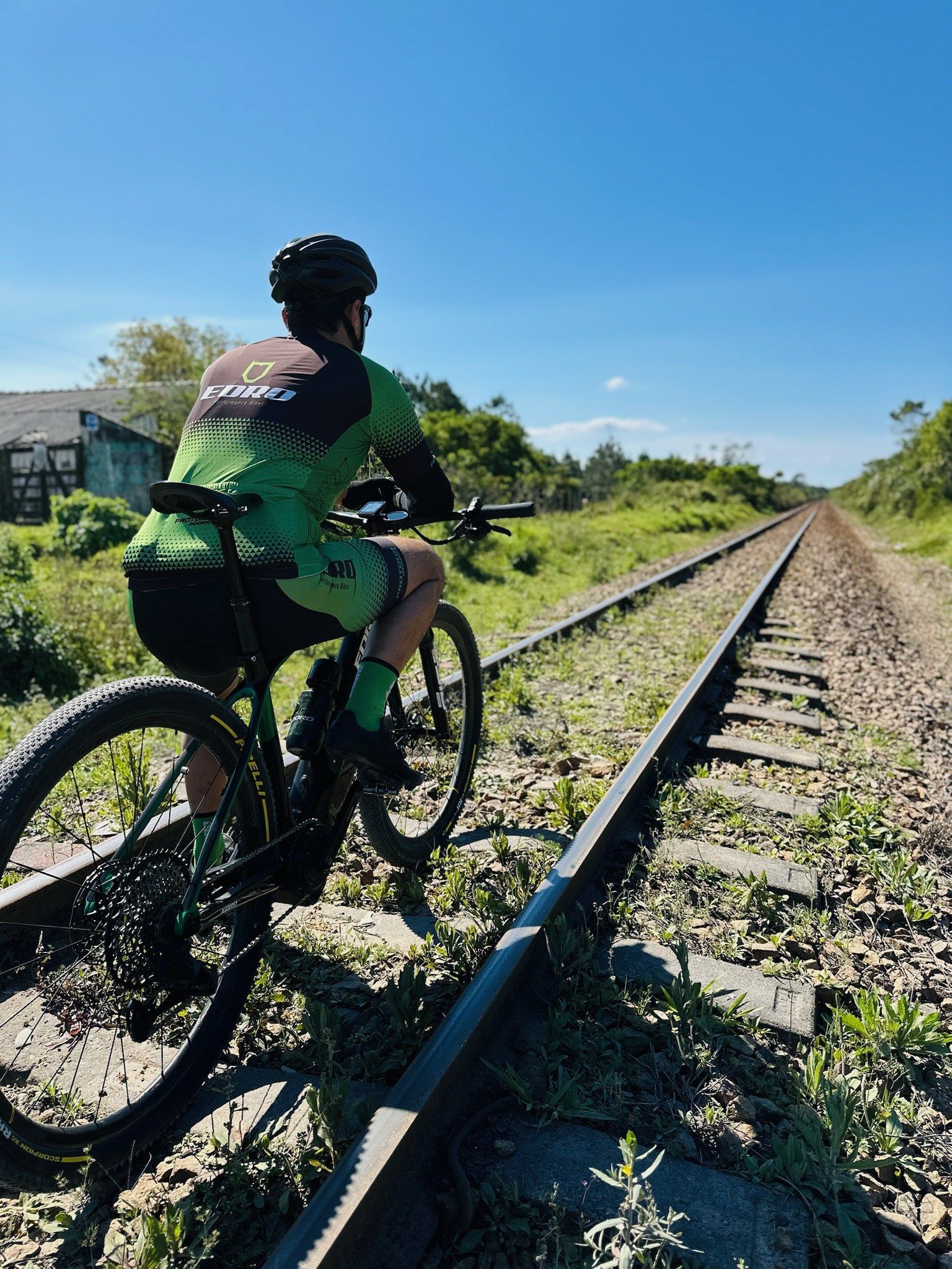 Ciclista pedalando a sua EDRO em uma trilha ao lado da linha do trem